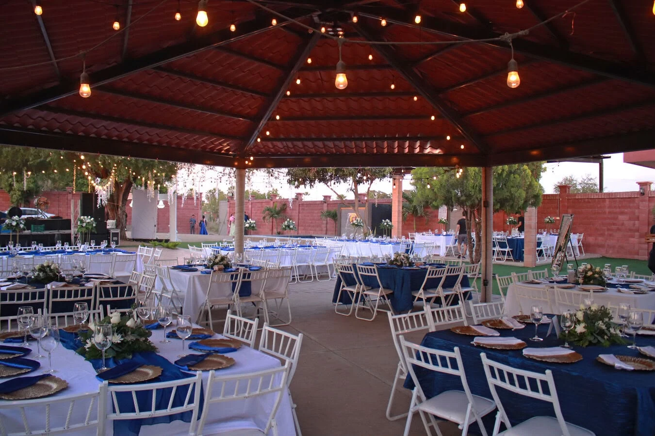 Montaje de mesas y cristalería bajo la terraza para celebrar una boda